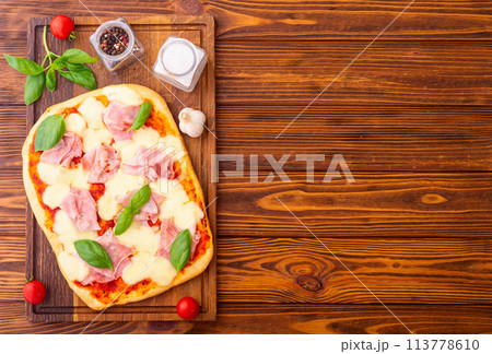 Traditional italian pizza with ham mozzarella and basil Traditional italian pizza with ham mozzarella and basil 113778610