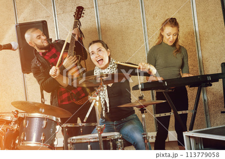 Passionate emotional female drummer with her bandmates practicin 113779058