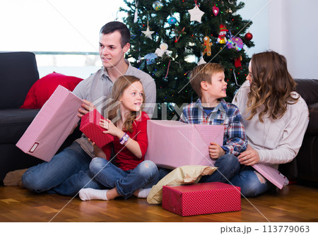 Large smiling family handing gifts during Christmas at home 113779063