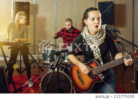Attractive female soloist playing guitar and singing with her mu 113779195
