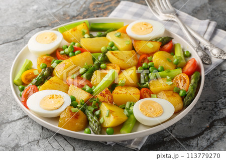 Delicious salad of potatoes, asparagus, cherry tomatoes, eggs and green peas close-up in a plate. Horizontal Delicious salad of potatoes, asparagus, cherry tomatoes, eggs and green peas close-up in a plate. Horizontal 113779270