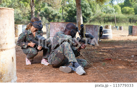 Two opposing teams shooting on paintball playing field outdoors Two opposing teams shooting on paintball playing field outdoors 113779333