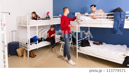 Two men travelers staying in cozy hostel, friendly talking to each other 113779571