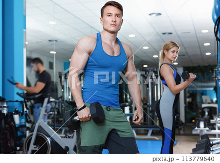 Portrait of athletic man exercising with dumbbells in gym Portrait of athletic man exercising with dumbbells in gym 113779640