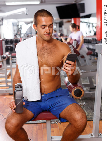 Sporty guy using smartphone at gym 113779742