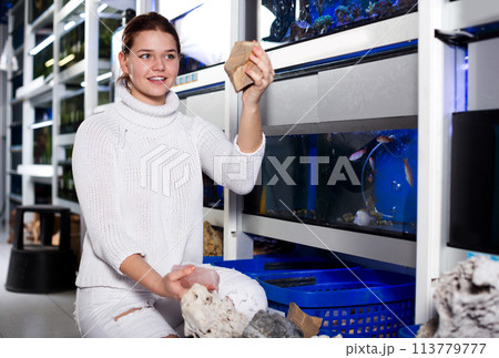 Girl choosing interesting large aquarian reefs Girl choosing interesting large aquarian reefs 113779777