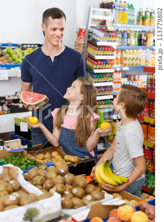 Man with preteen kids choosing fresh delicious fruits in supermarket Man with preteen kids choosing fresh delicious fruits in supermarket 113779802