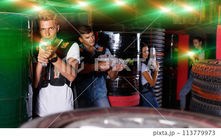 Young guy holding colored laser guns and took aim during laser t 113779973