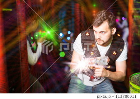 Guy in colored beams during laser tag game 113780011
