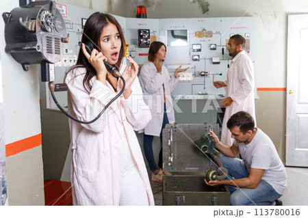 Young woman talking on telephone in lost room-bunker 113780016