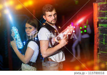 Couple standing back to back in laser beams 113780018