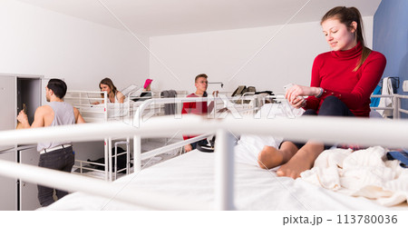 Girl with phone on bed in hostel Girl with phone on bed in hostel 113780036