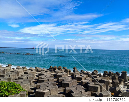 Hualien, Taiwan - 11.27.2022: A beach filled with tetrapod facing the Pacific Ocean with a lighthouse in sight under a sunny blue sky during the pandemic 113780762