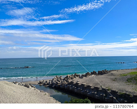 Hualien, Taiwan - 11.27.2022: Jian Stream leading to the Pacific Ocean via a beach with tetrapods on the side and people enjoying the beach on a sunny day under a blue sky during the pandemic 113780764