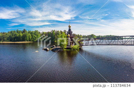 Aerial top view to wooden Church of St. Apostle Andrew First-Called on Vuoksa River with bridge. Temple on small island near village Vasilevo, Melnikovo, Priozersky District Leningrad region. Russia 113784634