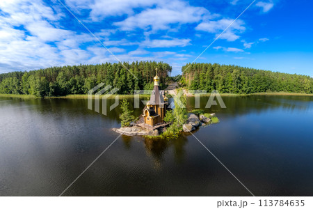 Aerial top view to wooden Church of St. Apostle Andrew First-Called on Vuoksa River with bridge. Temple on small island near village Vasilevo, Melnikovo, Priozersky District Leningrad region. Russia Aerial top view to wooden Church of St. Apostle Andrew First-Called on Vuoksa River with bridge. Temple on small island near village Vasilevo, Melnikovo, Priozersky District Leningrad region. Russia 113784635
