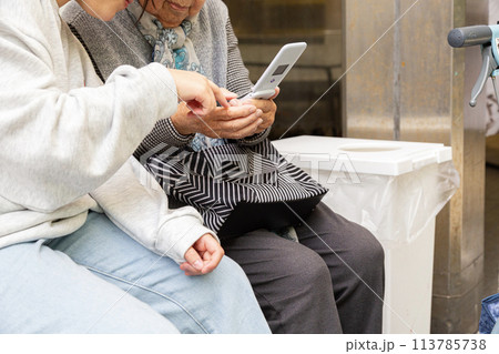 おばあちゃんに携帯電話の使い方を教える孫 おばあちゃんに携帯電話の使い方を教える孫 113785738