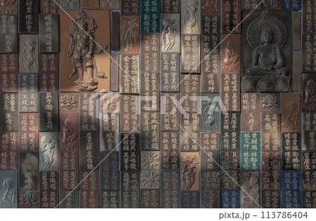 Chinese lettering teachings and Carved buddha images into a slab of colored tiles on temple wall. 113786404