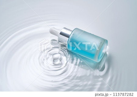 Bottles of cosmetics with a dropper in water on a blue background. 113787282
