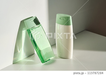 Shampoo and hair conditioner on a white background with sun light. 113787284