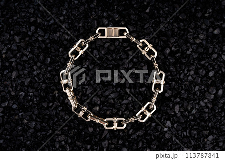 Gold bracelet on a background of black volcanic stones. 113787841