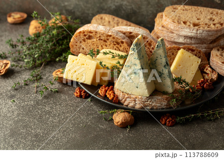 Cheese, bread, walnuts, and thyme on a stone kitchen table. 113788609