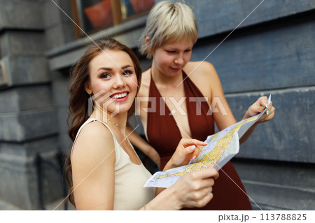 Happy young two women tourist travelers with paper map is exploring new city 113788825