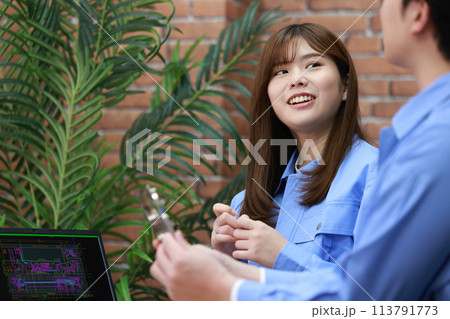 先輩から金属加工品の説明を受ける女性エンジニア_3 113791773