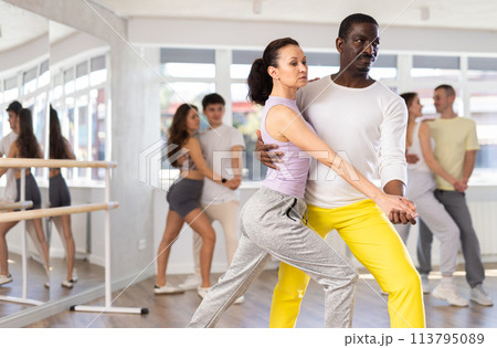 Middle-aged man and woman practicing tango dance in pair in training hall 113795089
