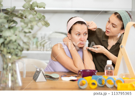 Two women looking at themselves in mirror Two women looking at themselves in mirror 113795365