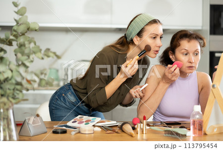 Two women applying makeup to themselves 113795454