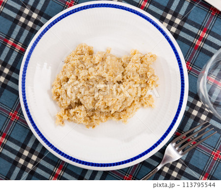 There is portion of freshly prepared milk oatmeal porridge in plate 113795544