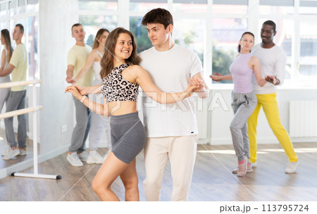 Young man and woman practicing salsa dance in pair in training hall Young man and woman practicing salsa dance in pair in training hall 113795724