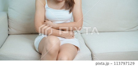woman having abdomen ache due to Stomach pain, digestion with constipation or Diarrhea from food poisoning, female problem and Endometriosis, Hysterectomy, Stomachache and Menstrual on sofa at home 113797129