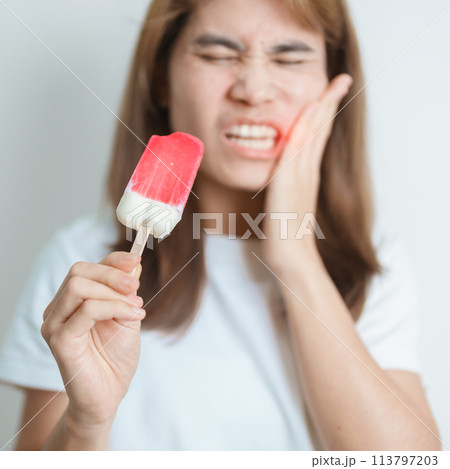 Teeth Sensitive to Cold concept. woman hold Ice cream and having toothache and pain after eat. Tooth Decay or Gum Disease, Grinding Teeth and Stress, Exposed Nerve Roots, Crack and Receding Gums 113797203