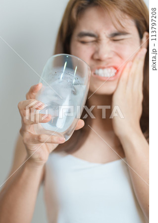 Teeth Sensitive to Cold concept. woman hold Ice Water glass and having toothache and pain after eat. Tooth Decay or Gum Disease, Grinding Teeth and Stress, Exposed Nerve Roots, Crack and Receding Gums 113797208