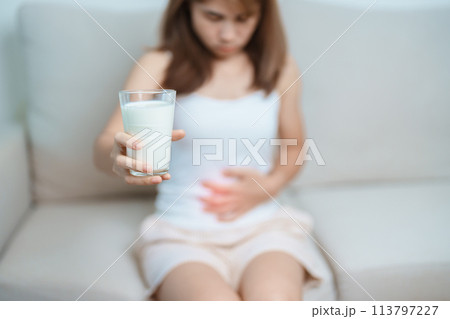 Lactose intolerance and Milk allergy concept. woman hold Milk glass and having abdominal cramps and pain when drink Cow Milk. Symptom stomach ache, Dairy intolerant, Nausea, Bloating, Gas and Diarrhea Lactose intolerance and Milk allergy concept. woman hold Milk glass and having abdominal cramps and pain when drink Cow Milk. Symptom stomach ache, Dairy intolerant, Nausea, Bloating, Gas and Diarrhea 113797227