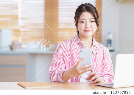 リビングでテレワークをしている若い女性。 リビングでテレワークをしている若い女性。 113797950
