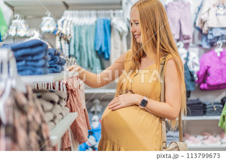 Expectant mother joyfully selects adorable clothes for her unborn baby while enjoying a shopping spree in the vibrant aisles of the shopping center 113799673