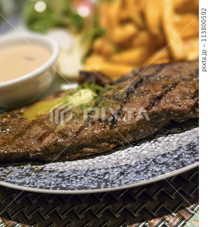 Beef New York strip loin steak or sirloin steak served with potatoes, and mushroom sauce and salad on plate 113800592
