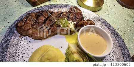 Beef New York strip loin steak or sirloin steak served with potatoes, and mushroom sauce and salad on plate 113800605