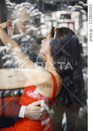 Photo in front of window of romantic couple standing and kissing inside 113802603