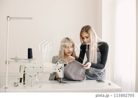 Two young seamstresses sitting on the sewing machine in her workshop 113802705