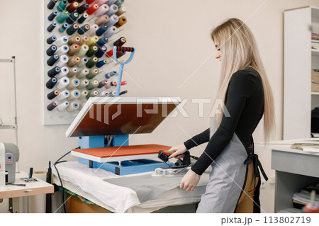 Young dressmaker standing in workshop near the bright wall with threads 113802719