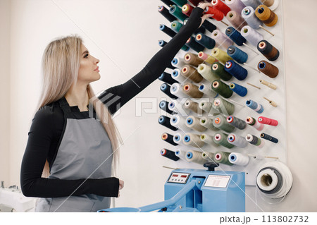 Female dressmaker standing in her workshop near the bright wall with threads 113802732