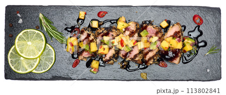 Sliced Organic grilled Tuna fillet covered with sesame seeds on black stone serving board 113802841