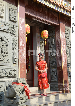 Portrait pretty Asian female in red traditional Chinese costume standing and posing in the shrine. 113804675