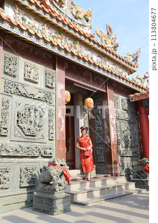 Portrait pretty Asian female in red traditional Chinese costume standing and posing in the shrine. 113804677