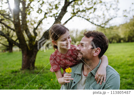 Father looking at his daughter lovingly in spring nature. Father's day concept. Father looking at his daughter lovingly in spring nature. Father's day concept. 113805487