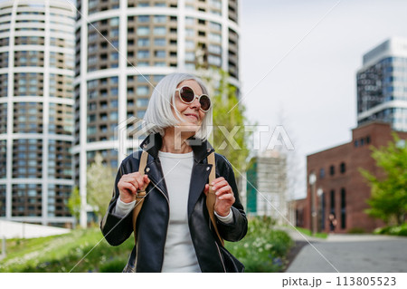 Portrait of stylish mature woman with gray hair on city street. Older woman in sunglasses waiting for public transport. Portrait of stylish mature woman with gray hair on city street. Older woman in sunglasses waiting for public transport. 113805523